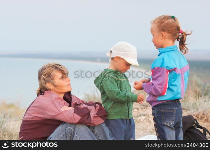 mother with small girl and boy on evening prairie near sea coast