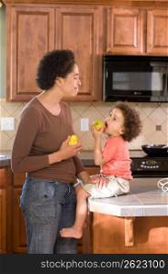 Mother with son (2-3) holding fruits in kitchen
