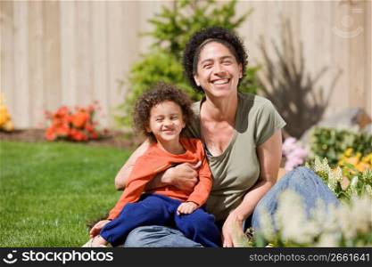 Mother with son (2-3) in garden, smiling