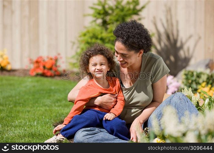 Mother with son (2-3) in garden, smiling