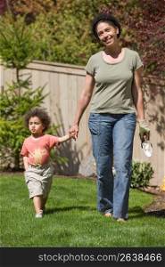 Mother with son (2-3) walking in garden, smiling
