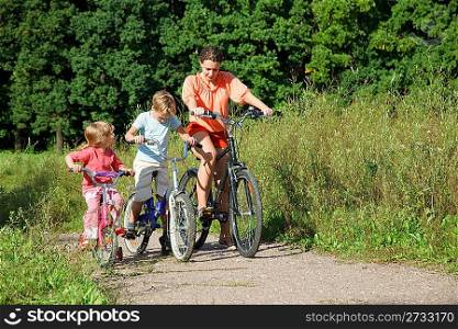 Mother with son and daughter ride bikes outside the city