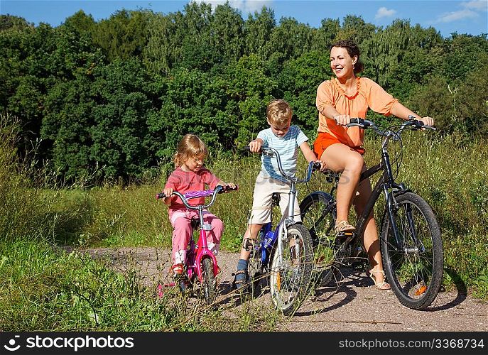 Mother with son and daughter ride bikes outside the city
