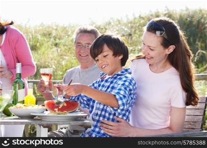 Mother With Son And Grandfather Enjoying Outdoor Barbeque