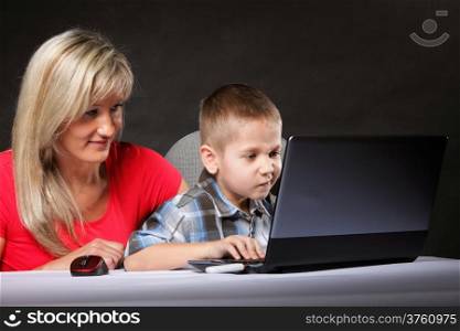 mother with son together looking on the laptop black background