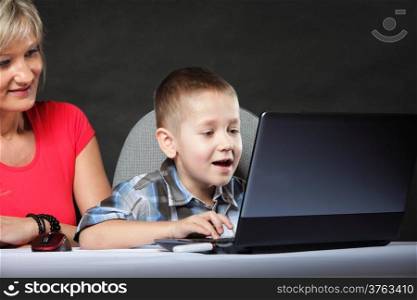 mother with son together looking on the laptop computer black background