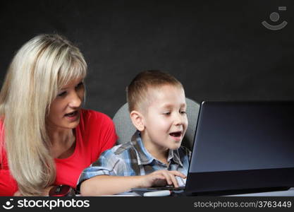 mother with son together looking on the laptop computer black background