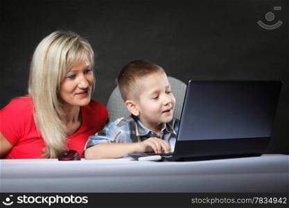 mother with son together looking on the laptop computer black background