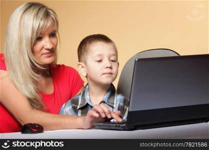 mother with son together looking on the laptop orange background