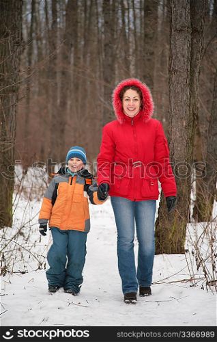 mother with son walk in forest in winter