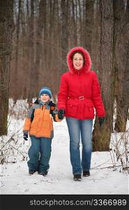 mother with son walk in forest in winter