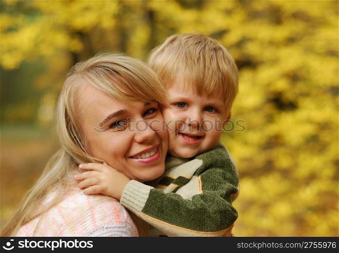 Mother with the child. On a background of yellow autumn foliage
