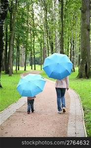 mother with the child under the umbrellas in the park