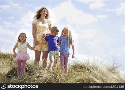 Mother with three children on dunes, Wales, UK