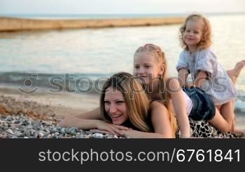 mother with two daughters at the beach during sunset
