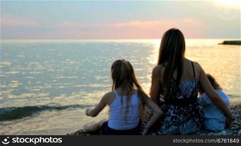 mother with two daughters at the beach during sunset