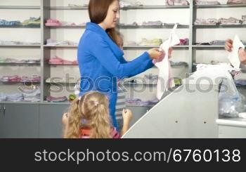 Mother with two daughters shopping for girls clothes in a clothing store, looking kids underwear