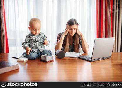 Mother works at home little kid helps her, motherhood problems. Sad mom and son together at home. Mother works, kid helps her, motherhood problems