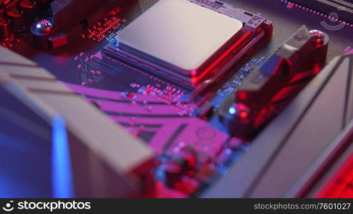 Motherboard with processor close up tilt shot. Computer components on circuit board lit with red and blue ligths.. Motherboard with processor close up shot