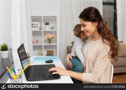 motherhood, multi-tasking, family and people concept - happy mother with baby and laptop working at home. happy mother with baby and laptop working at home