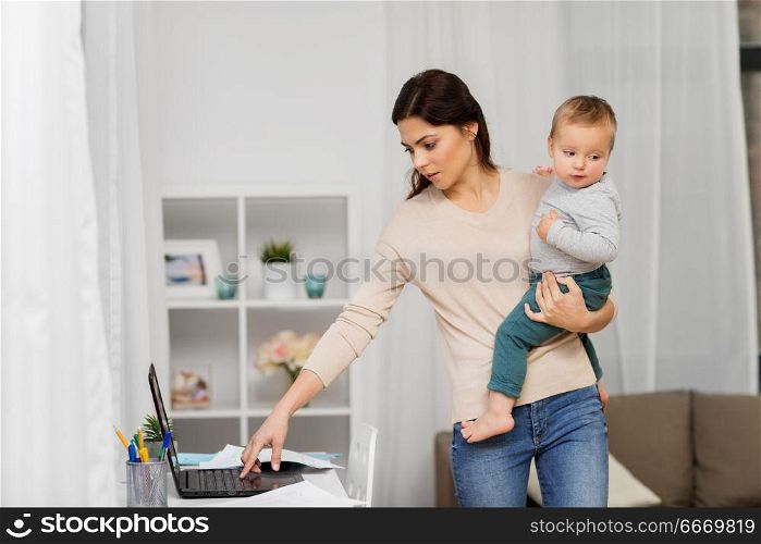 motherhood, multi-tasking, family and technology concept - mother with baby, laptop computer and papers working at home. mother with baby and laptop working at home. mother with baby and laptop working at home