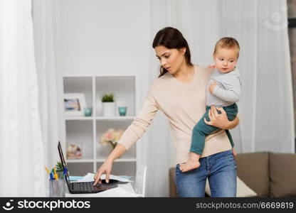 motherhood, multi-tasking, family and technology concept - mother with baby, laptop computer and papers working at home. mother with baby and laptop working at home. mother with baby and laptop working at home