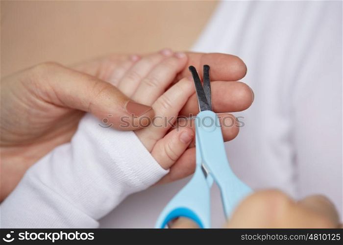 motherhood, people and child care concept - close up of mother hand with scissors trimming baby nails