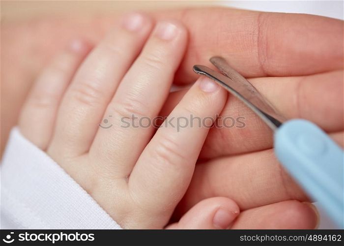 motherhood, people and child care concept - close up of mother hand with scissors trimming baby nails