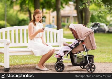 motherhood, technology and people concept - happy mother with smartphone and baby girl stroller at summer park. happy mother with smartphone and stroller at park