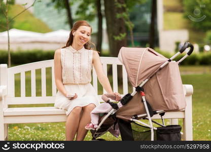 motherhood, technology and people concept - happy mother with smartphone and baby girl stroller at summer park. happy mother with smartphone and stroller at park