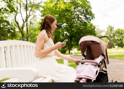 motherhood, technology and people concept - happy mother with smartphone and baby girl stroller at summer park. happy mother with smartphone and stroller at park