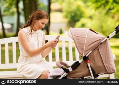 motherhood, technology and people concept - happy mother with smartphone taking picture of her baby stroller at summer park. happy mother with smartphone and stroller at park