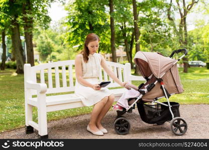 motherhood, technology and people concept - happy mother with tablet pc computer and baby girl stroller at summer park. happy mother with tablet pc and stroller at park