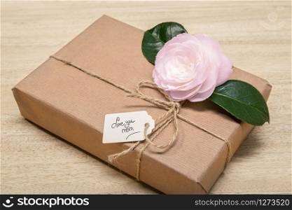 Mothers day concept. Gift box with label and flower. Hand made text Love you Mom