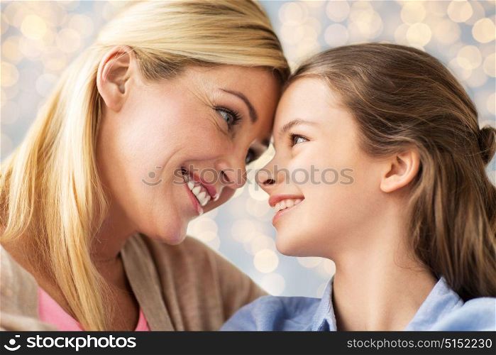 mothers day, people and family concept - happy smiling girl with mother over lights background. happy family of girl and mother