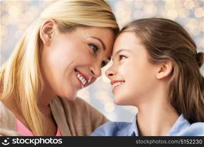 mothers day, people and family concept - happy smiling girl with mother over lights background. happy family of girl and mother