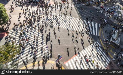 Motion blur of Crowded people walking and car traffic transport on Shibuya scramble crossing, high angle view. Tokyo tourist attraction, Japan tourism, Asia transportation or Asian city life concept