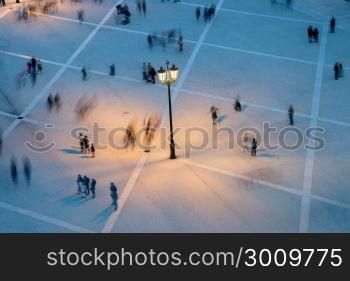 Motion blur of many people on a public square at twilight. View from above