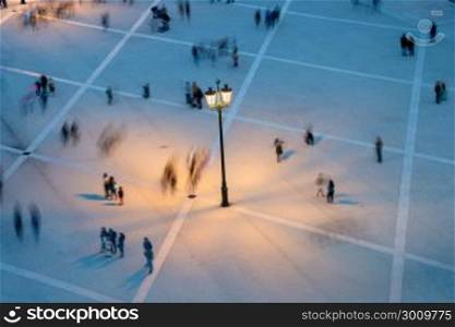 Motion blur of many people on a public square at twilight. View from above