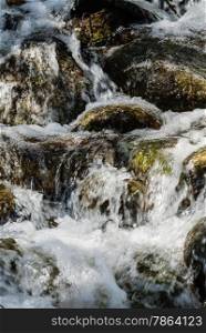 Motion blur of water cascading over mossy rocks.