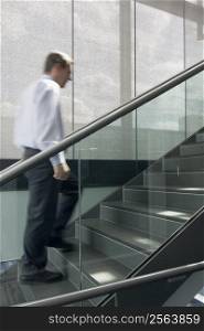 Motion blurred image of businessman climbing a stairway in an office building
