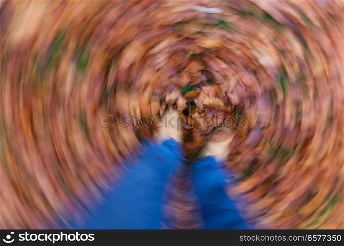 Motion blurred photograph of man or womans feet walking through golden Fall or Autumn leaves