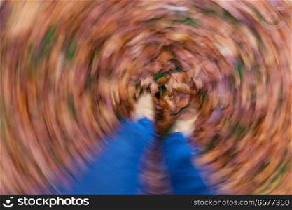 Motion blurred photograph of man or womans feet walking through golden Fall or Autumn leaves