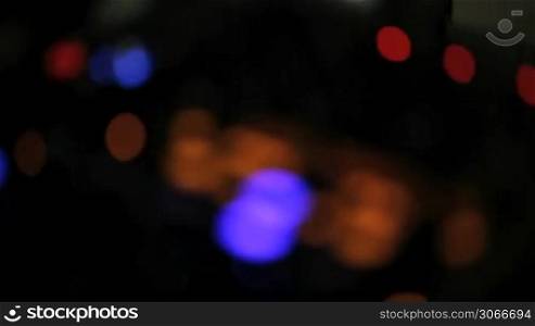 Motion clip moving in and out of focus on a disc jockeys colourful lights on a sound deck at night