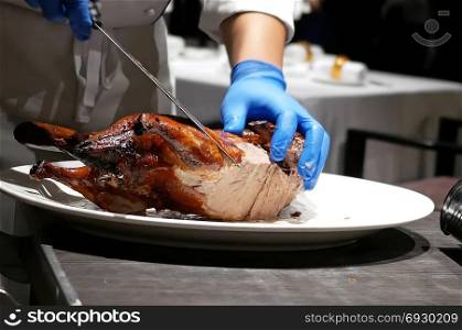 Motion of chef cutting roasted duck into a plate for customer