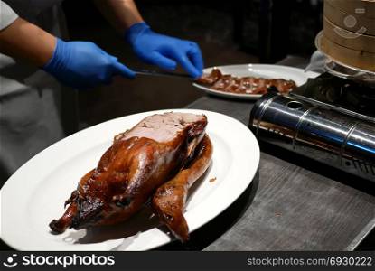 Motion of chef cutting roasted duck into a plate for customer inside Chinese restaurant