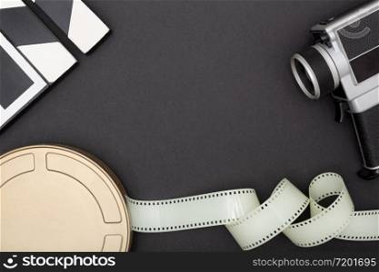 Motion Picture Film Can, film camera and film strip on black background. Movie or TV background. Top view Copy space