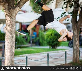Motion shot of a young sportsman doing acrobatics in the city. Front flip trick. Young athlete doing extreme acrobatics outdoor