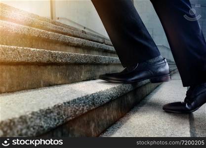 Motivation and challenging Career Concept. Steps Forward into a Success. Low Section of Businessman Walking Up on Staircase. Male in Black Formal Dress