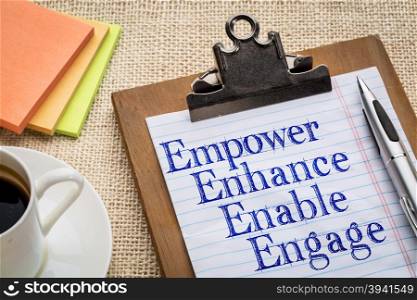motivational leadership, coaching or business concept - empower, enhance, enable and engage words on a clipboard with a cup of coffee